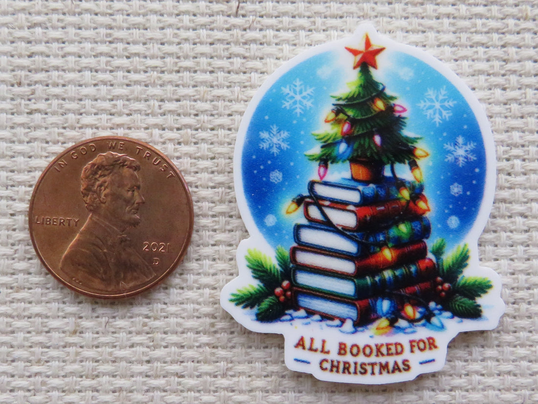 Small Christmas tree sitting on top of a stack of colorful books with a string of lights in front of a winter night circle with the words "All booked for Christmas" minder.