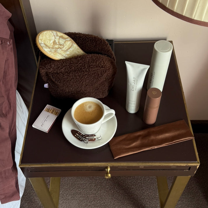 Assorted Emi Jay hair car, accessories, and pouch on table with coffee.